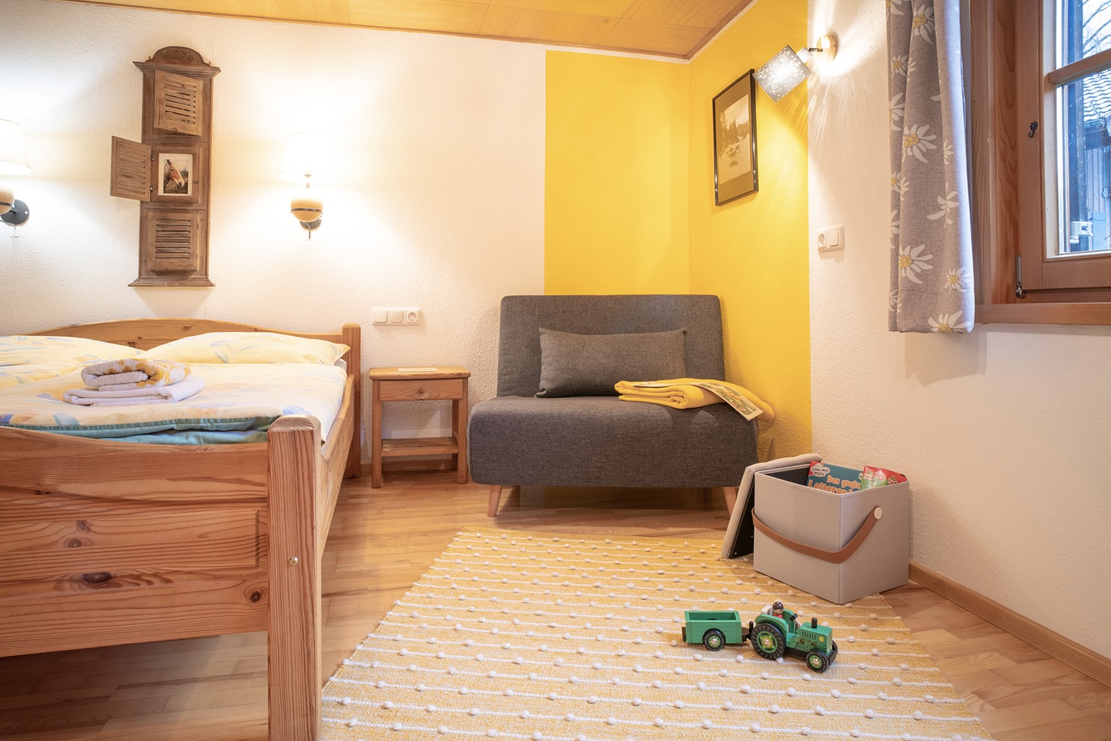 Doppelbett und Spielecke mit gelbem Wandakzent und Wollteppich