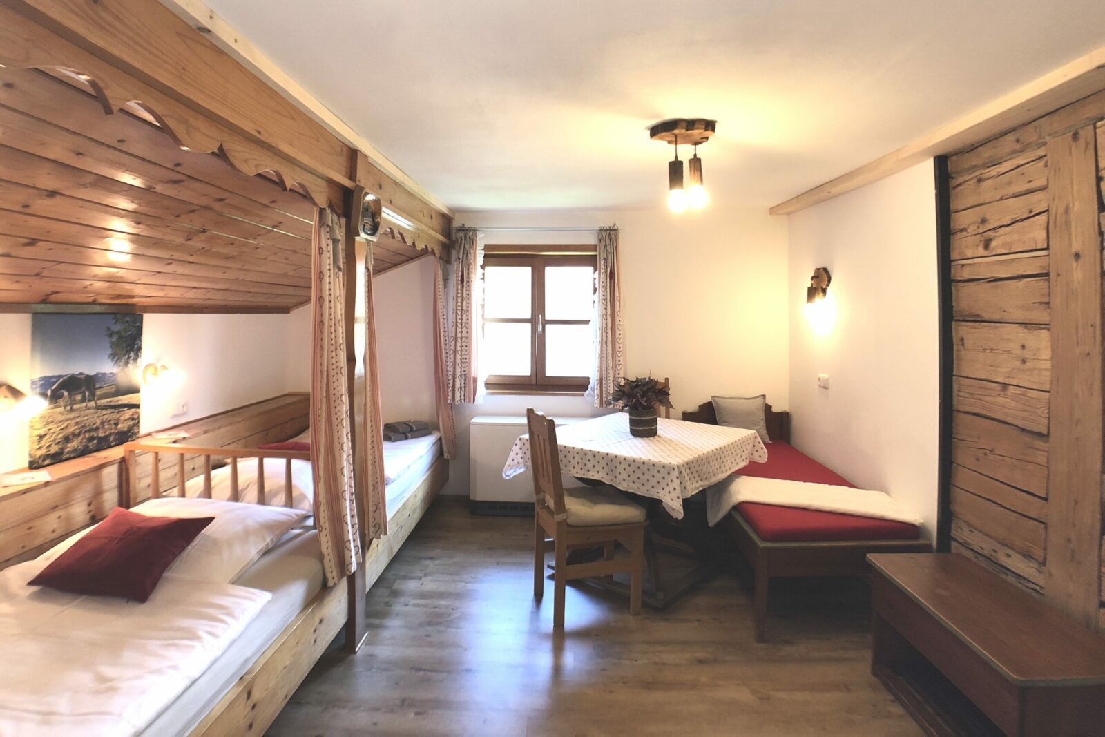 Kinderzimmer in der Ferienwohnung Bergblick im Bauernhaus. Zwei große Kojenbetten und Kanapee. Blick auf freigelegte historische Holzbalken.